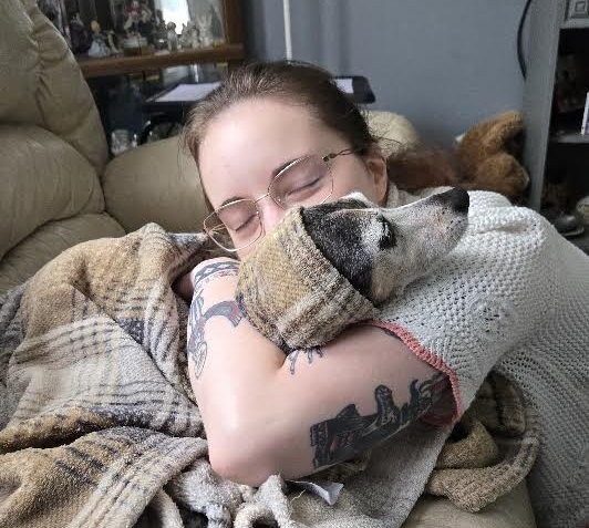 Allison of Nakama Pet Services cuddling a dog wrapped in a blanket